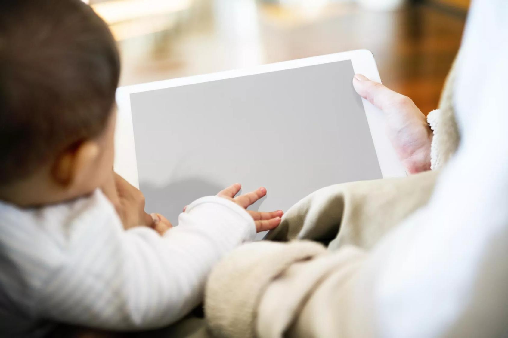 A baby and his parent use a tablet together.