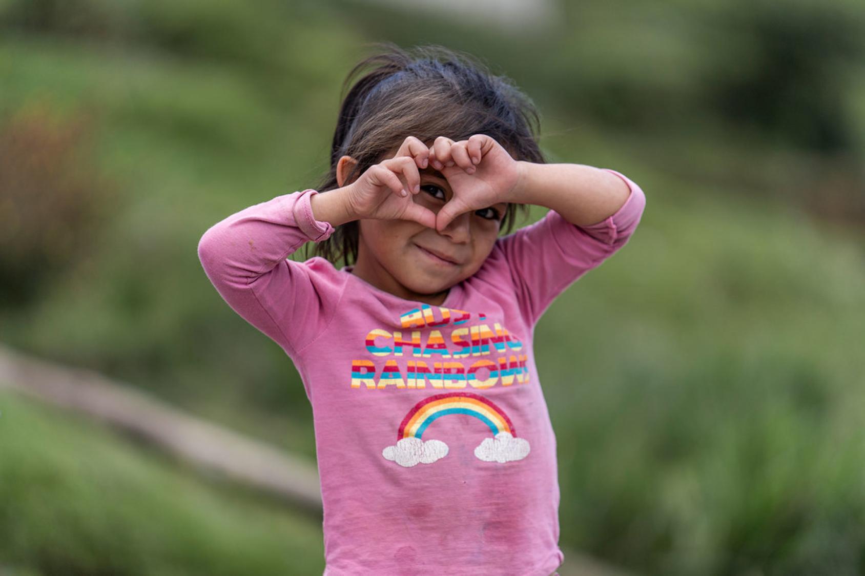 A girl makes a heart symbol with her hands.