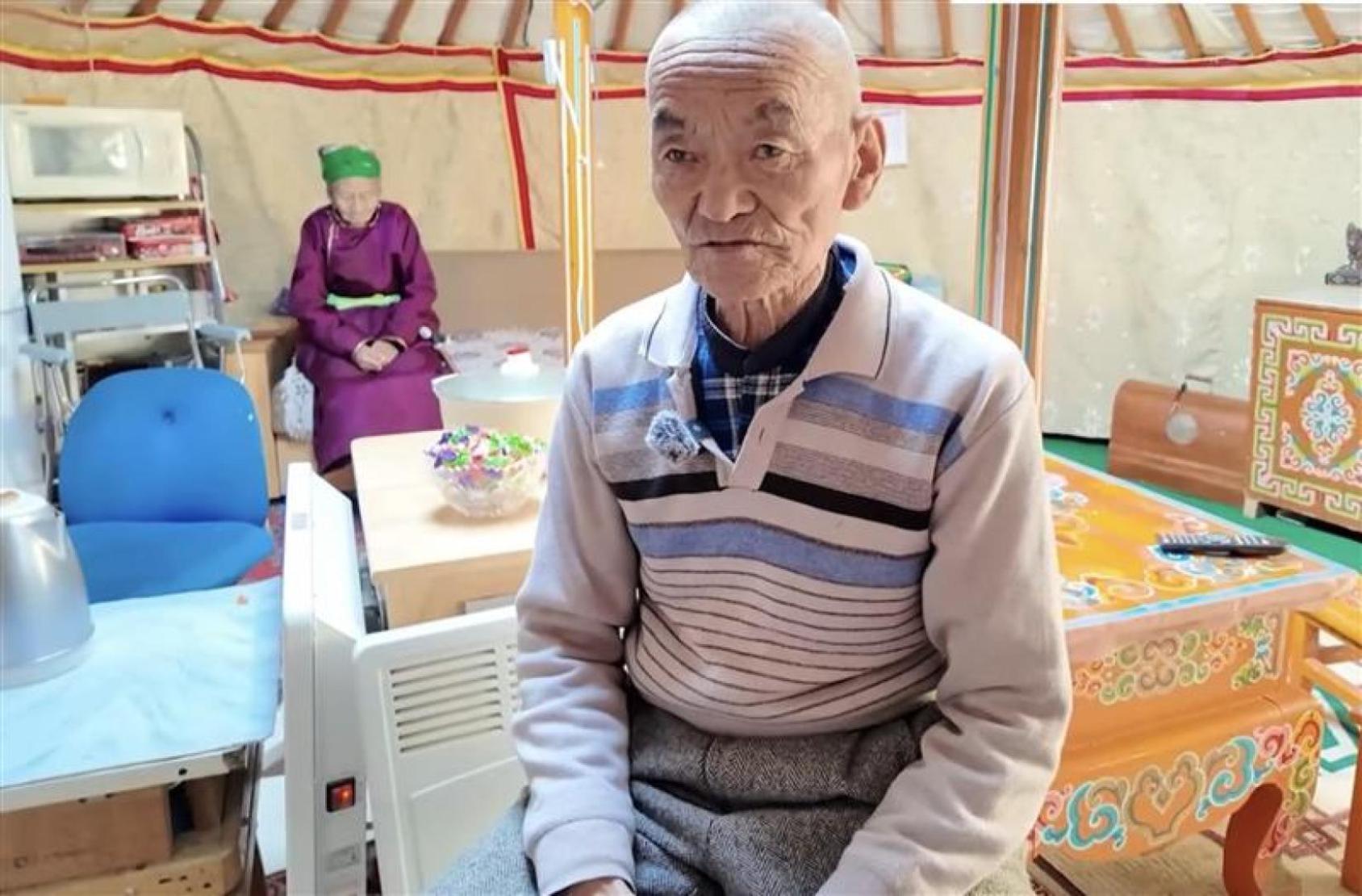 Пожилой мужчина сидит внутри традиционной юрты.