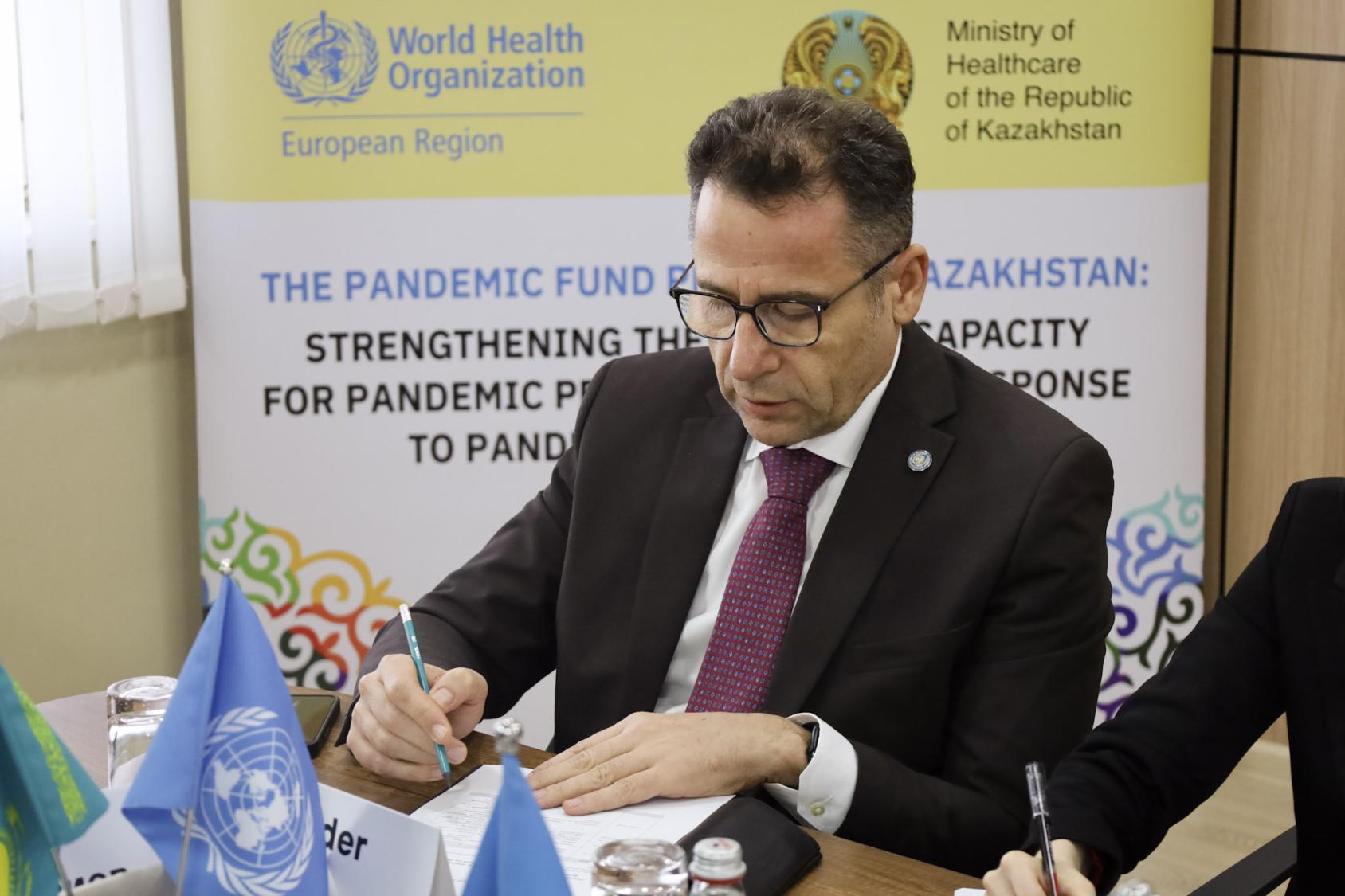 Представитель ВОЗ подписывает документы.