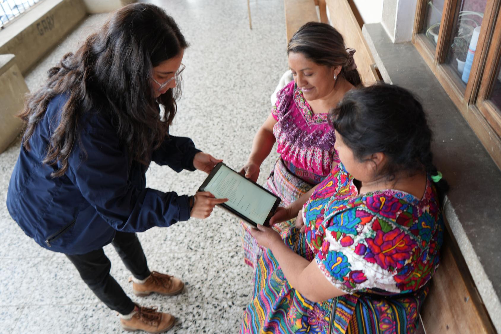 Three women in Guatemala use a tablet.
