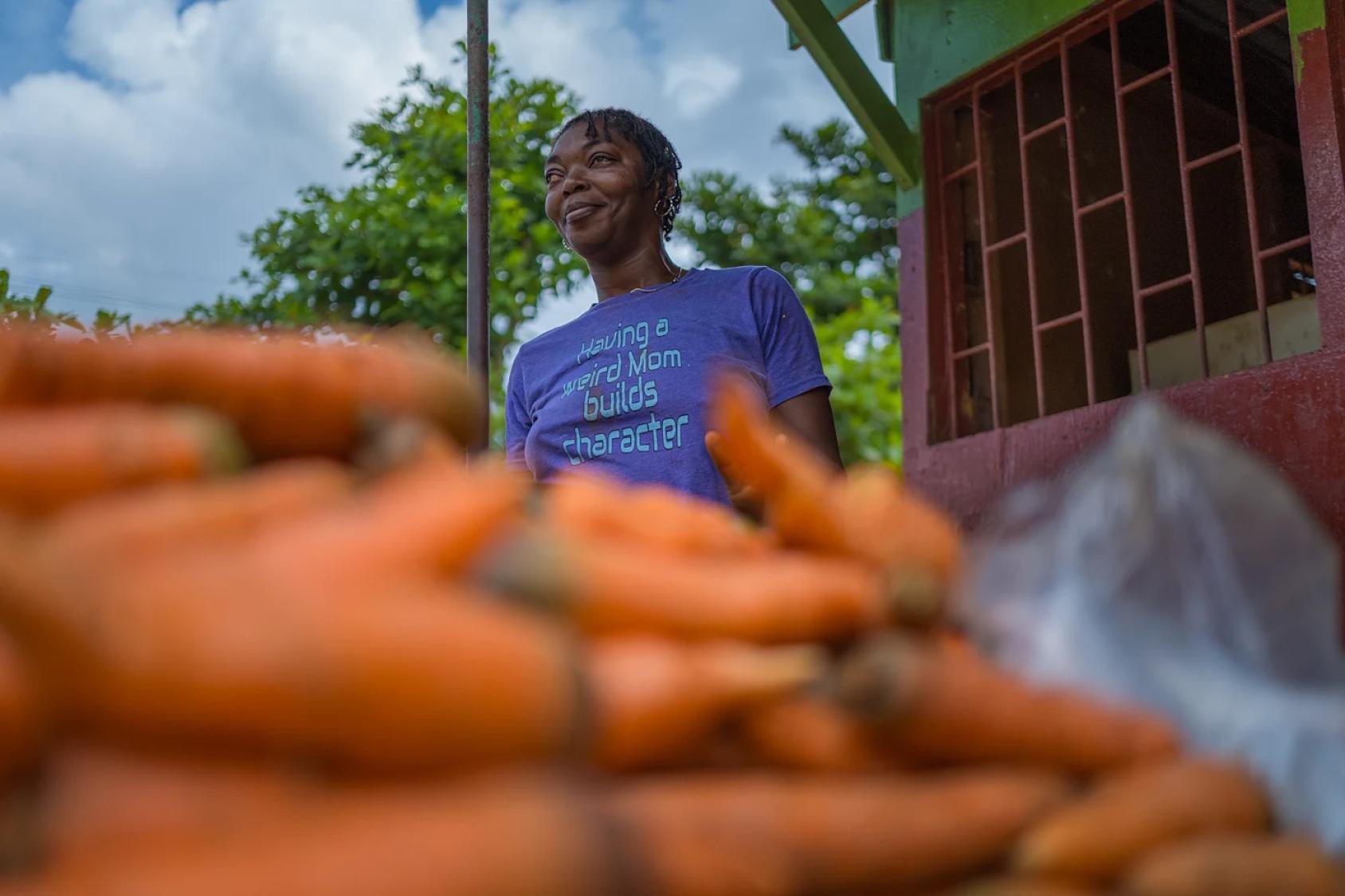 A woman in Jamaica in front of a carrot stand. 