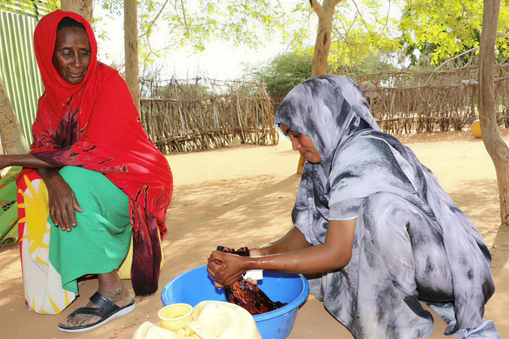 Two women in Kenya wash their clothes by hand. 