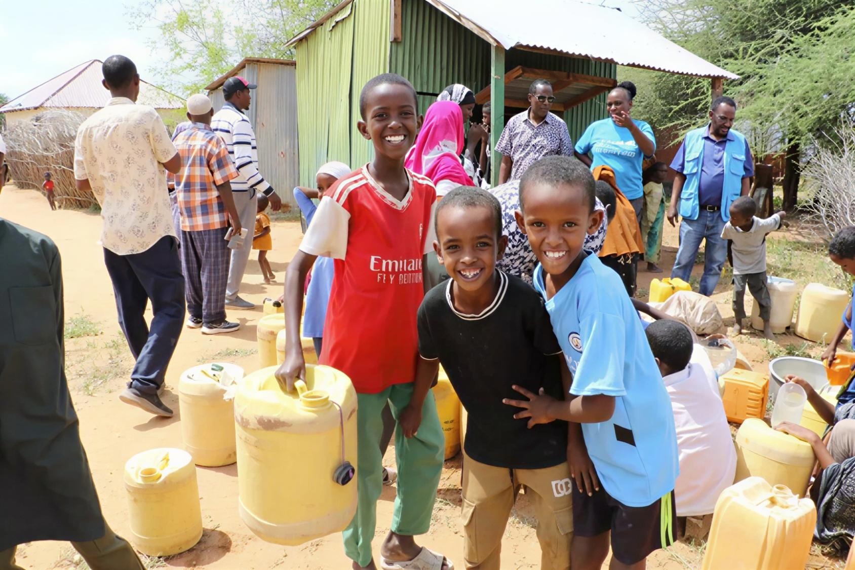 Three boys in Kenya among water containers.