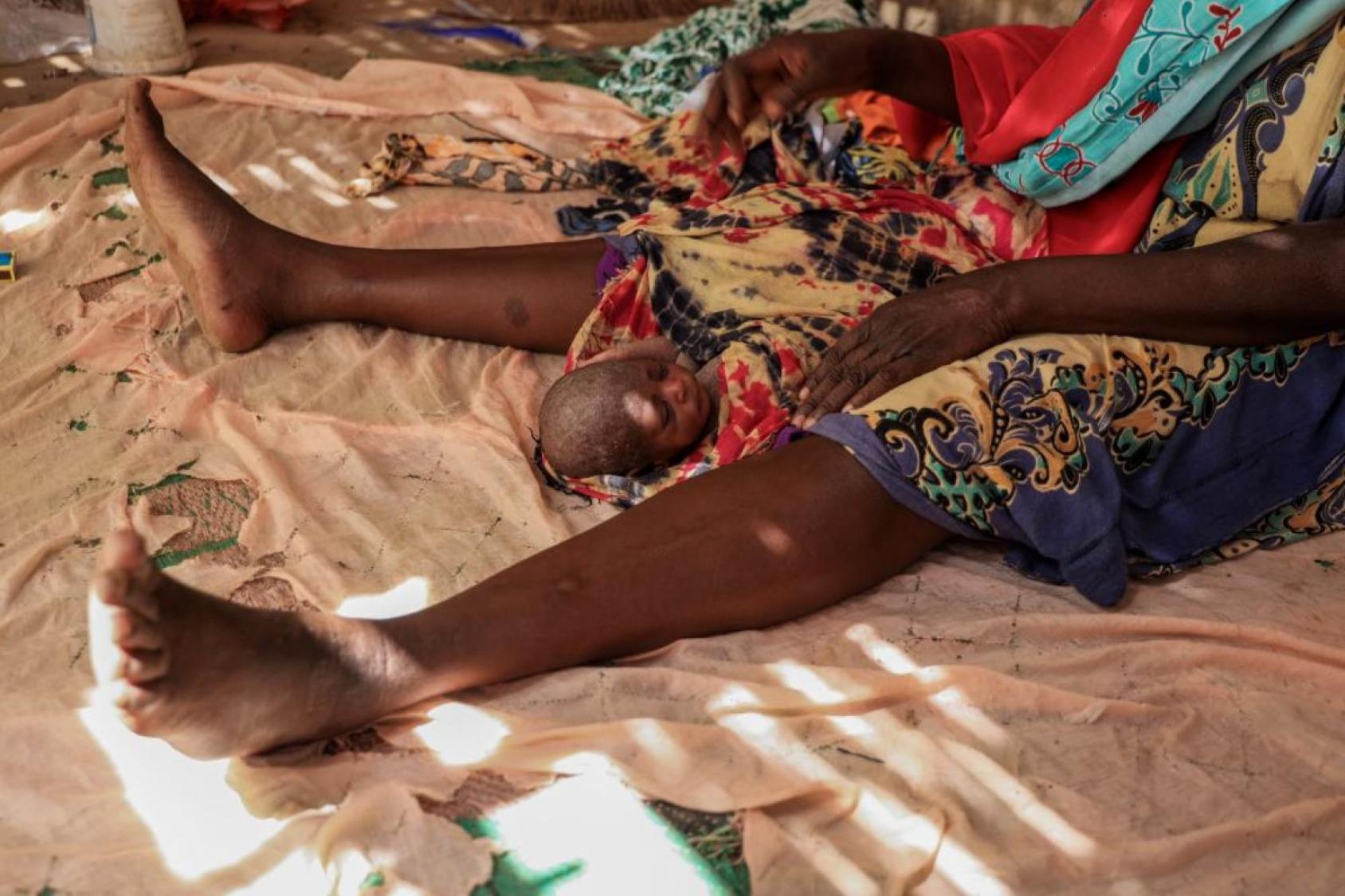 Un nouveau-né sur un tissu entre les jambes d’une femme adulte allongés 