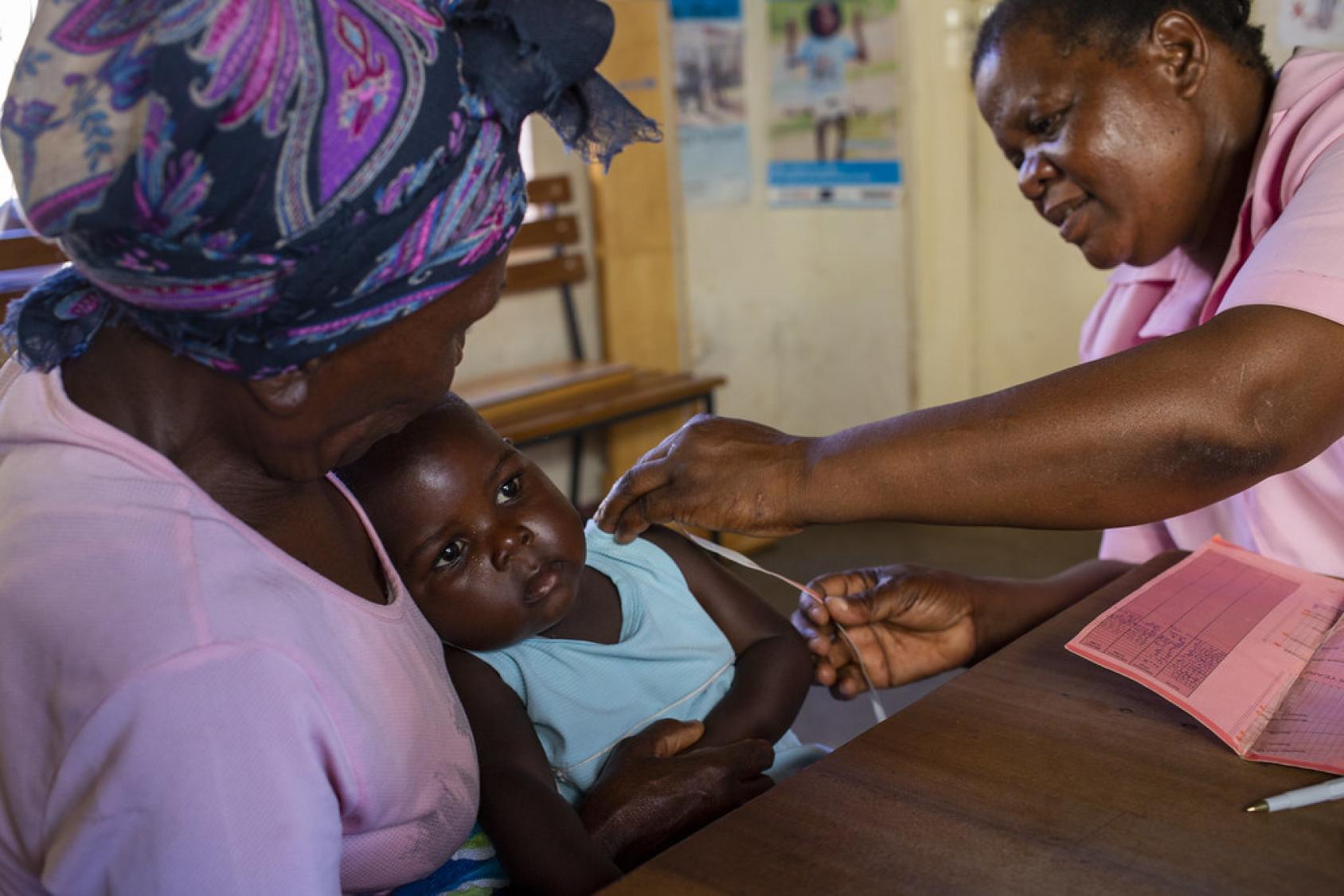 A woman in Zimbabwe holds her granddaughter as she receives a vaccine. 