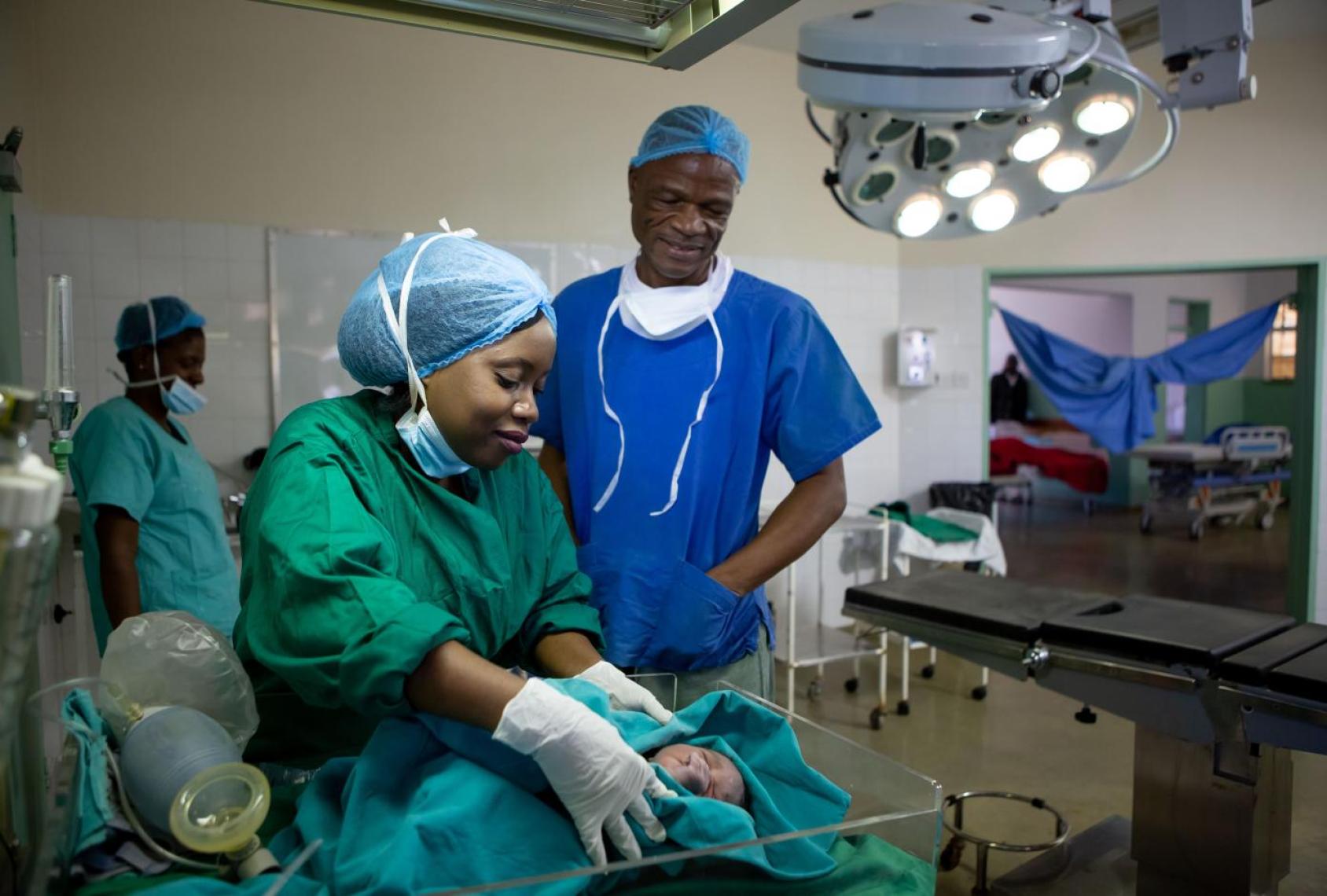 A doctor and nurse in Zimbabwe attend to a baby in a hospital.