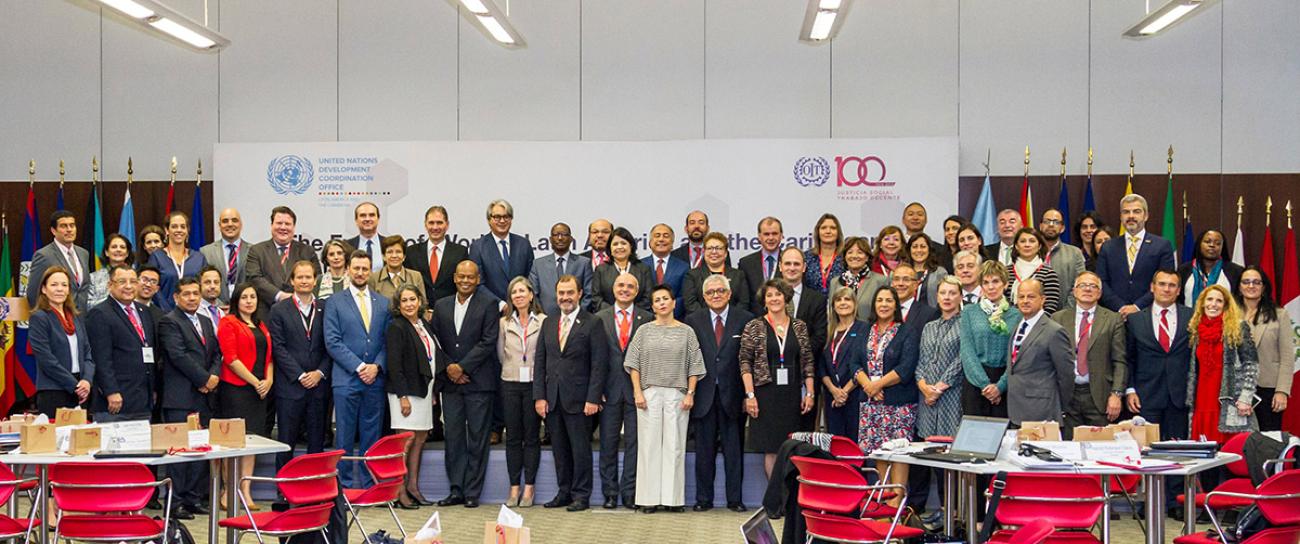 Representantes de la Oficina de Coordinación del Desarrollo y de la OIT delante de una pancarta con los logotipos de ambas entidades.