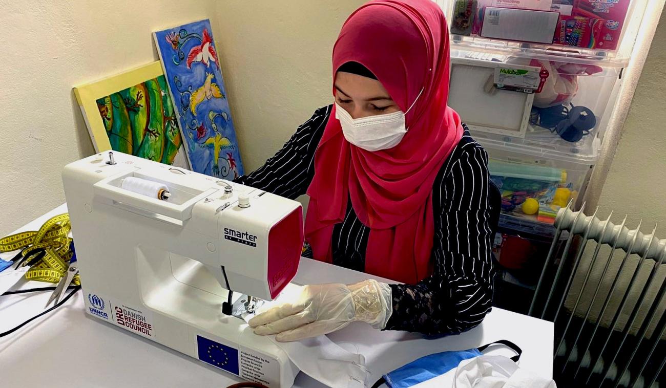 Se muestra a una mujer cosiendo una mascarilla protectora.