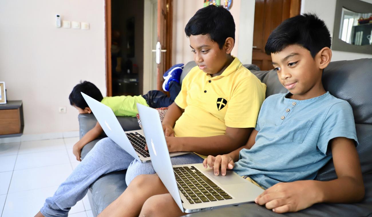 نسينا صبي يبلغ من العمر 12 عامًا وشقيقه أنتسو البالغ من العمر 8 سنوات يعملان على الكمبيوتر في منزلهما في برازافيل.