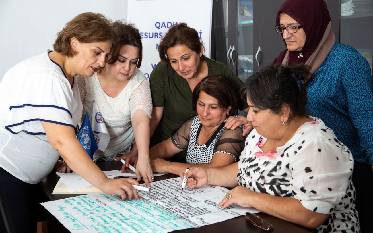 Seis personas trabajando en un material sobre una mesa.