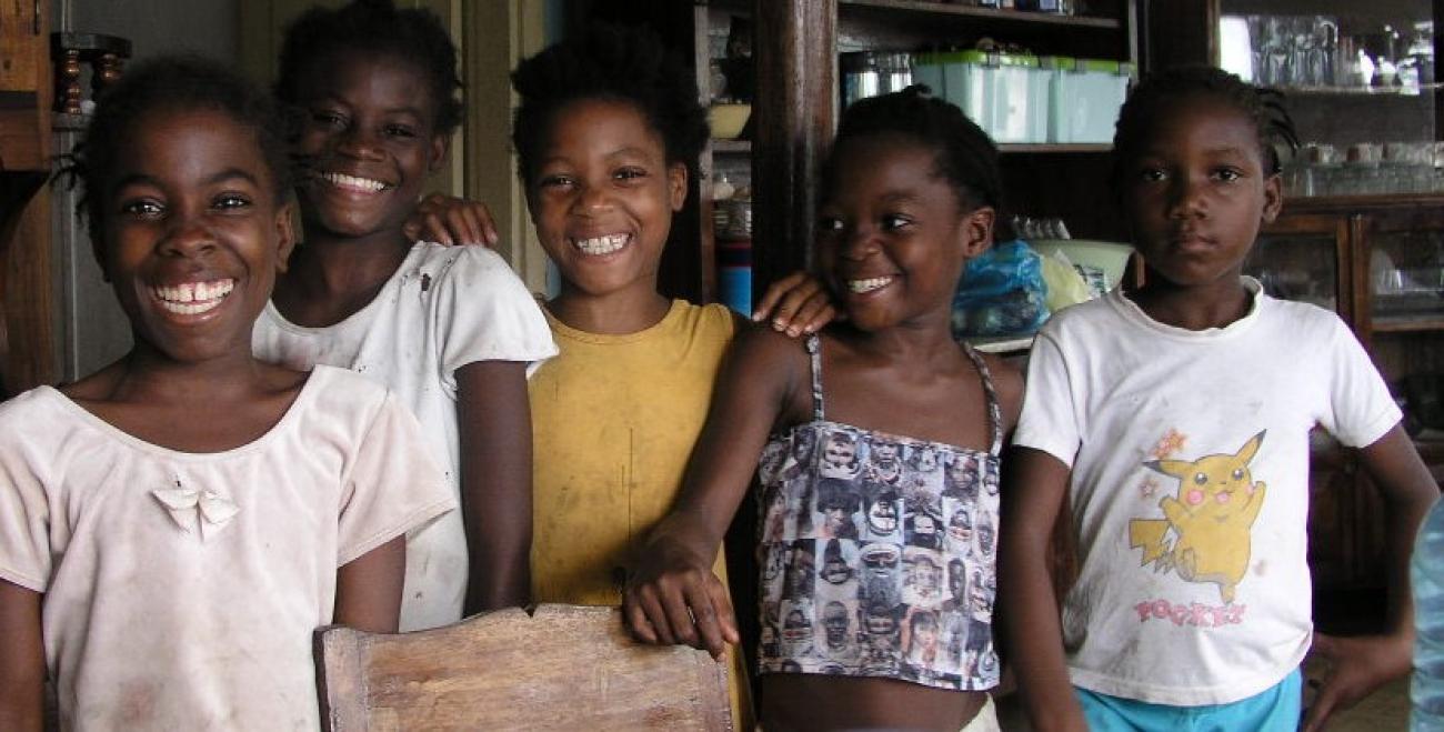 تقف خمس فتيات صغيرات من ساو تومي وبرينسيبي بالقرب من بعضهن البعض ويبتسمن بسعادة أمام الكاميرا.