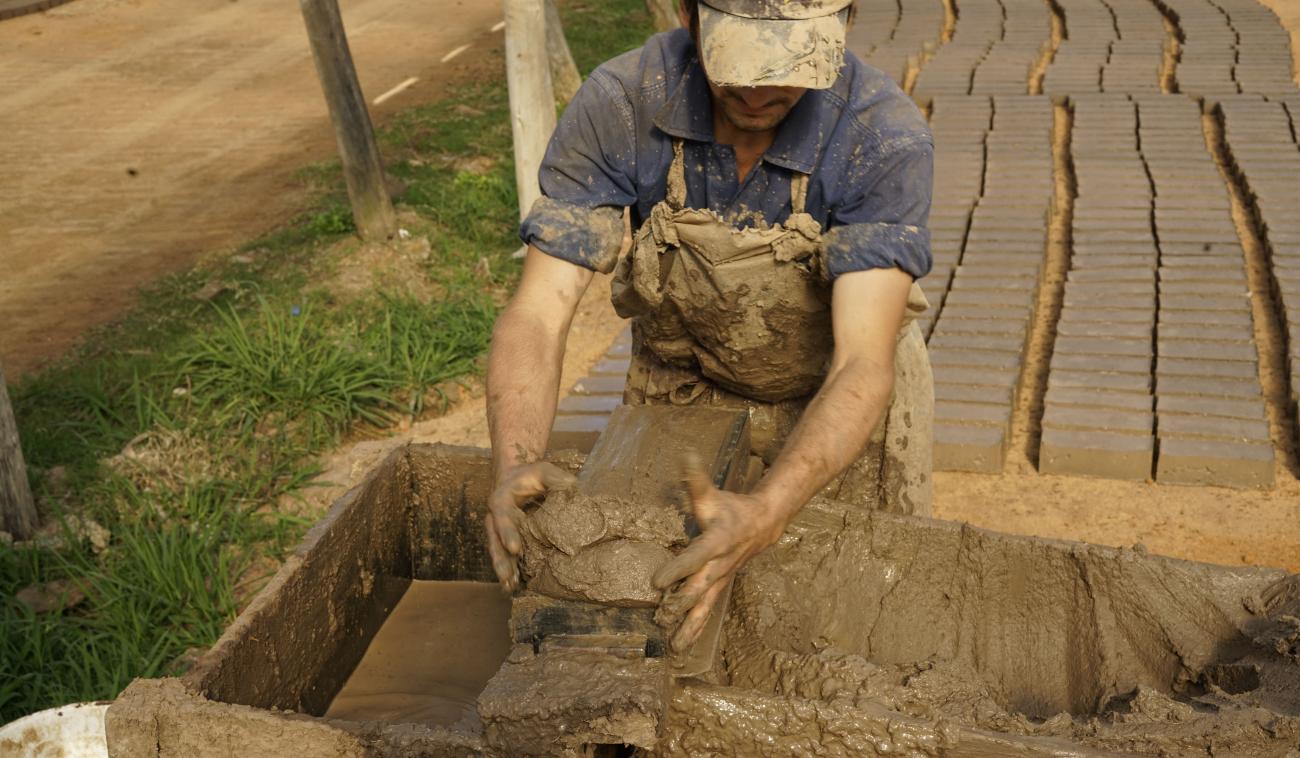 Photo d'un briquetier en train de mouler des briques à la main.