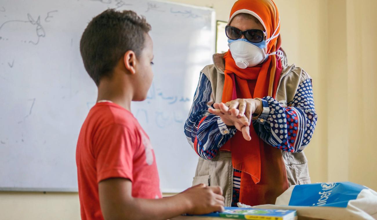 موظفة في الأمم المتحدة تقدم شرحًا حول السلامة لصبي صغير ومجموعة لوازم النظافة.