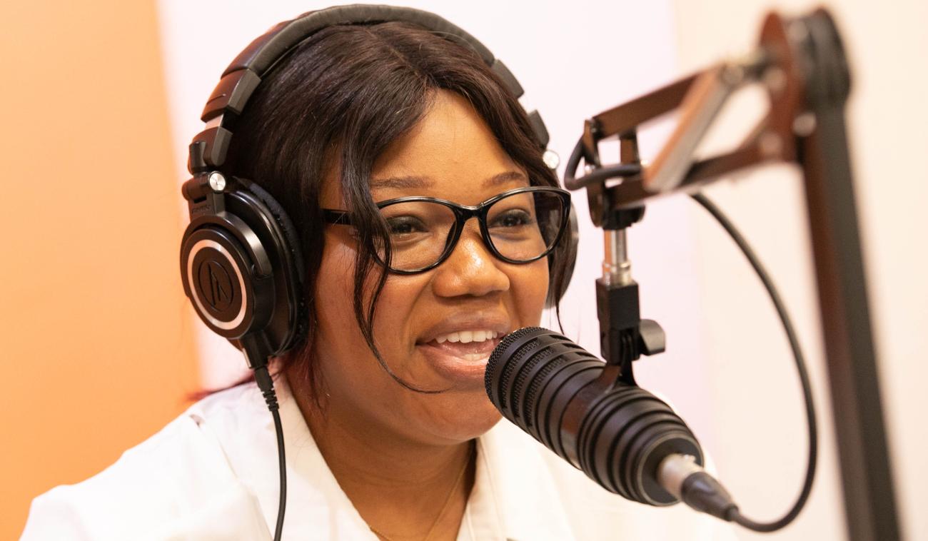 شابة ترتدي سماعات الأذن وتتحدث أمام ميكروفون محطة الراديو.