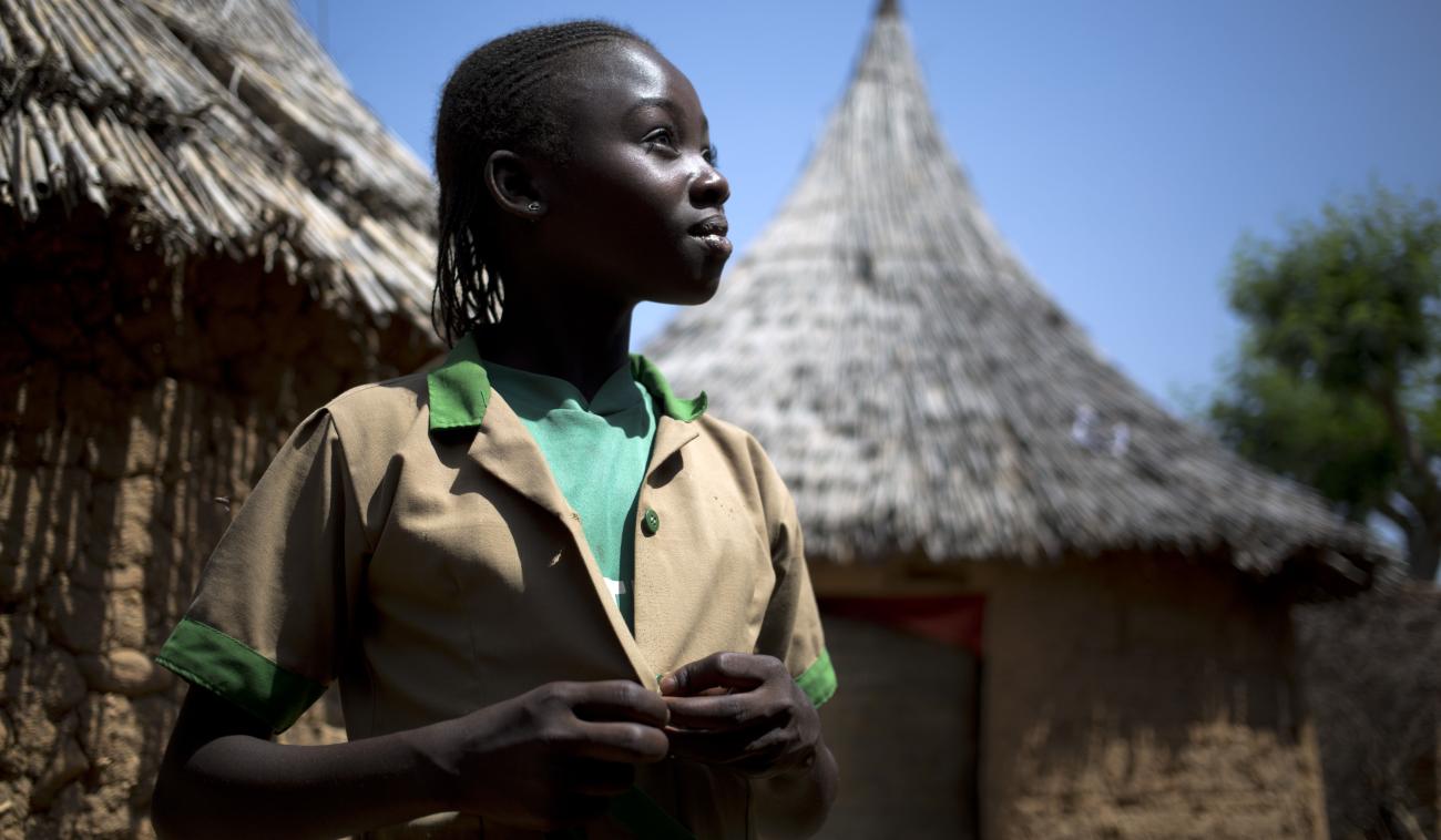 فتاة صغيرة تقف بفخر وتنظر إلى الأمام مباشرة.