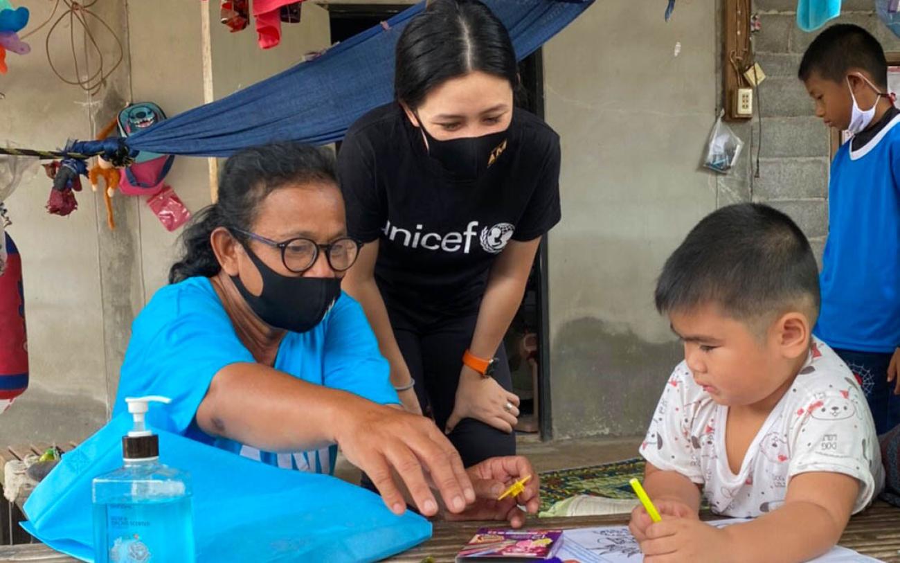 Rasa Pattikasemkul, une volontaire de l'UNICEF (au centre), s'entretient avec un jeune garçon lors d'un rare face-à-face pendant le confinement mis en place en réponse à la pandémie de COVID-19.