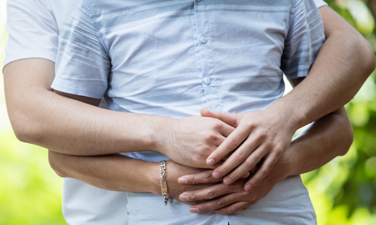 جذع رجلين أحدهما يحتضن الآخر من الخلف.