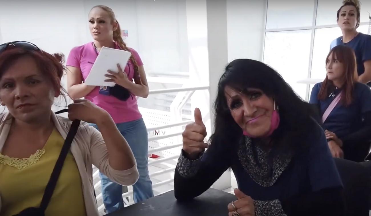 Trans women together at the programme, one smiles and gives a thumbs up to the camera.