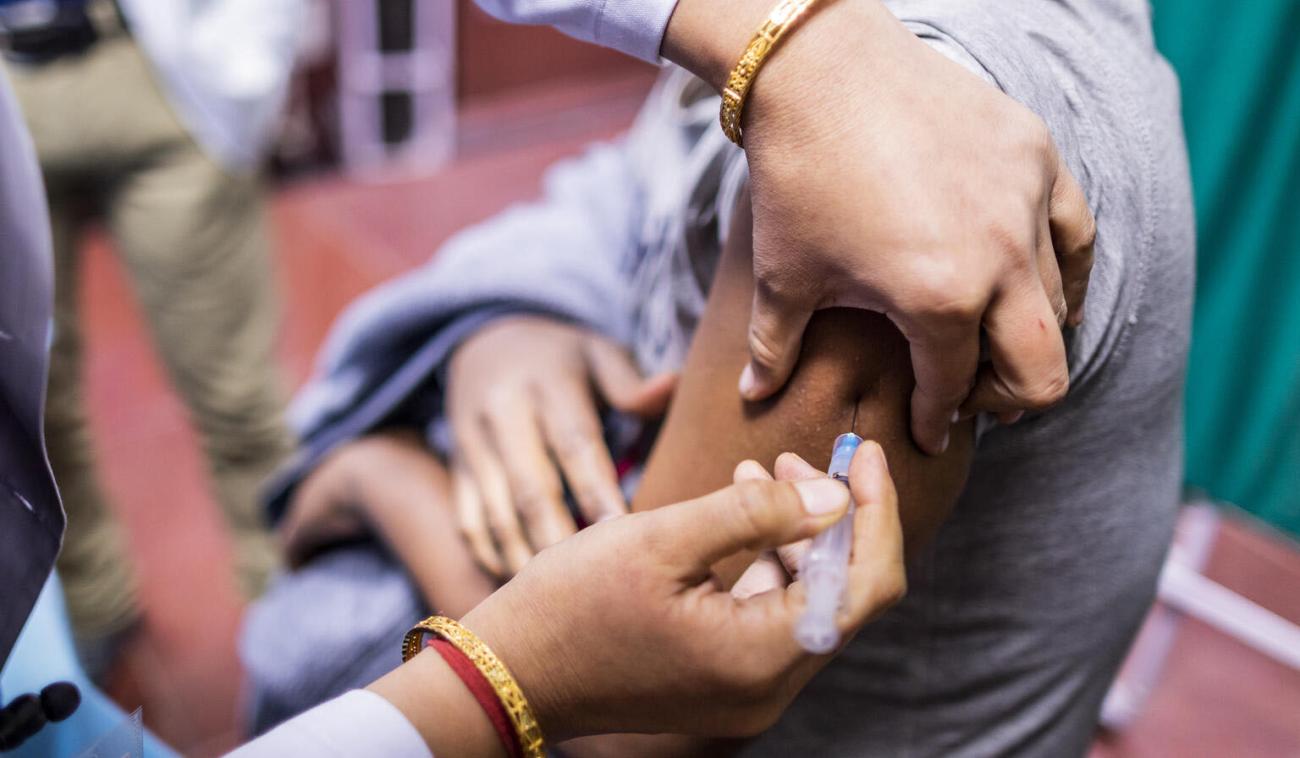 Gros plan d'un soignant administrant le vaccin anti-COVID-19 à une personne.