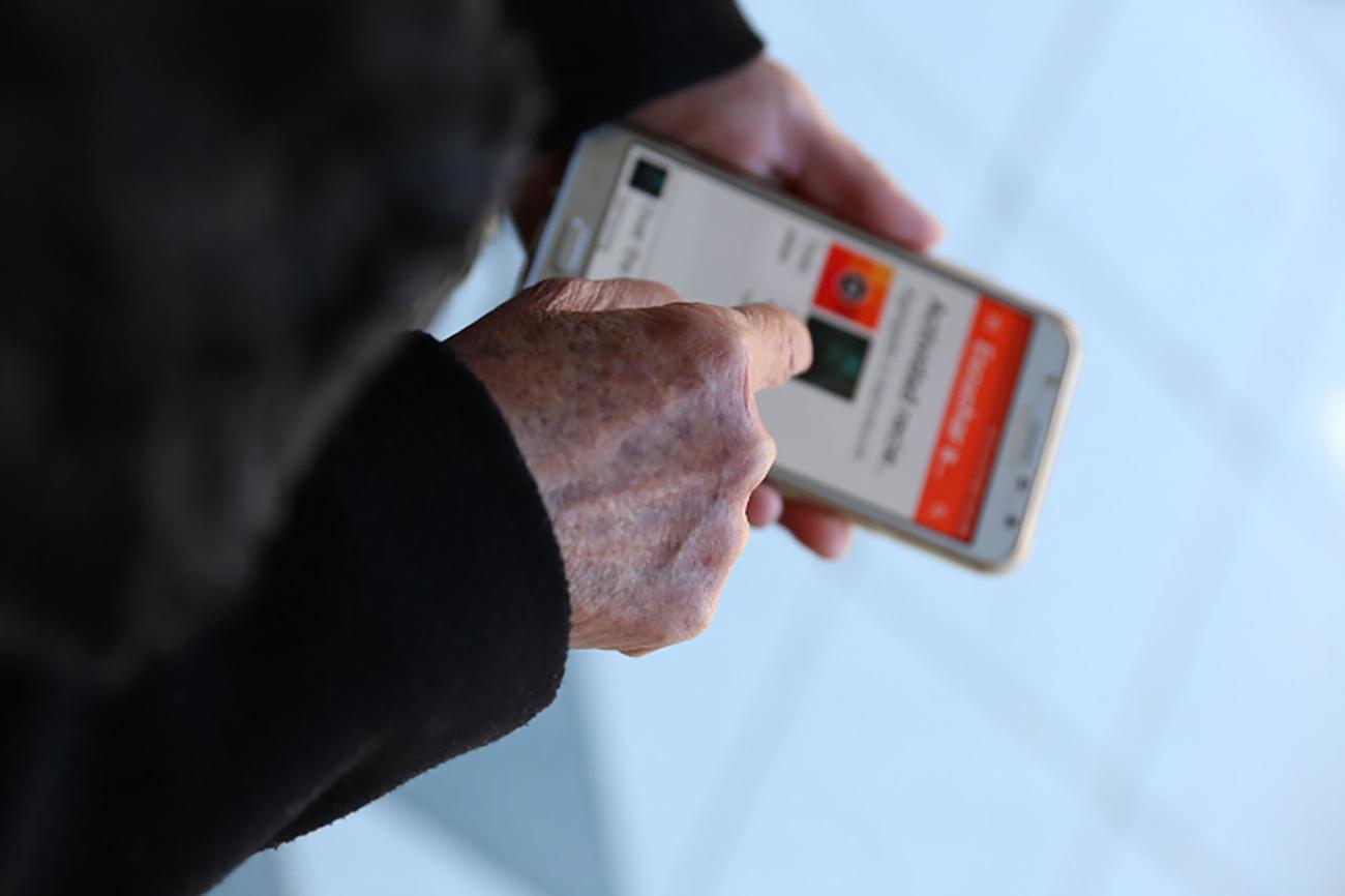 لقطة مقرّبة ليدي شخص يستخدم تطبيقًا على هاتفه الخلوي.