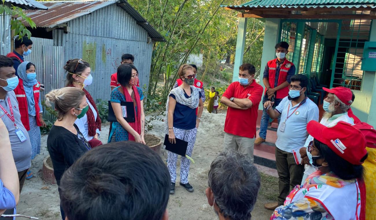 مجموعة كبيرة من الأشخاص يرتدون كمامات ويقفون في الخارج على شكل دائرة.