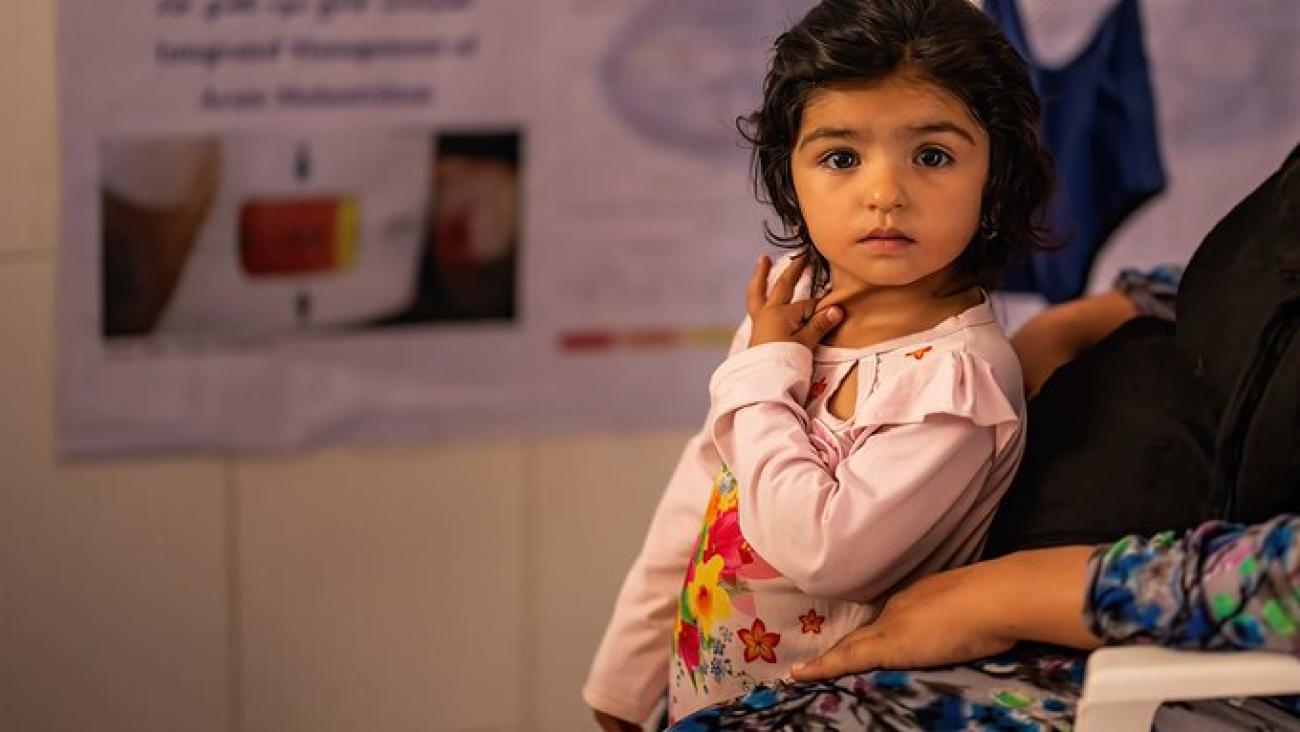 فتاة صغيرة ترتدي قميصًا ورديًا تنظر مباشرة إلى الكاميرا.