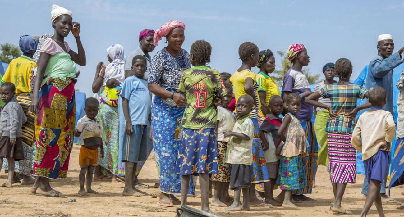 A group of women, men and children gather outside in a camp in the northeast of the country.