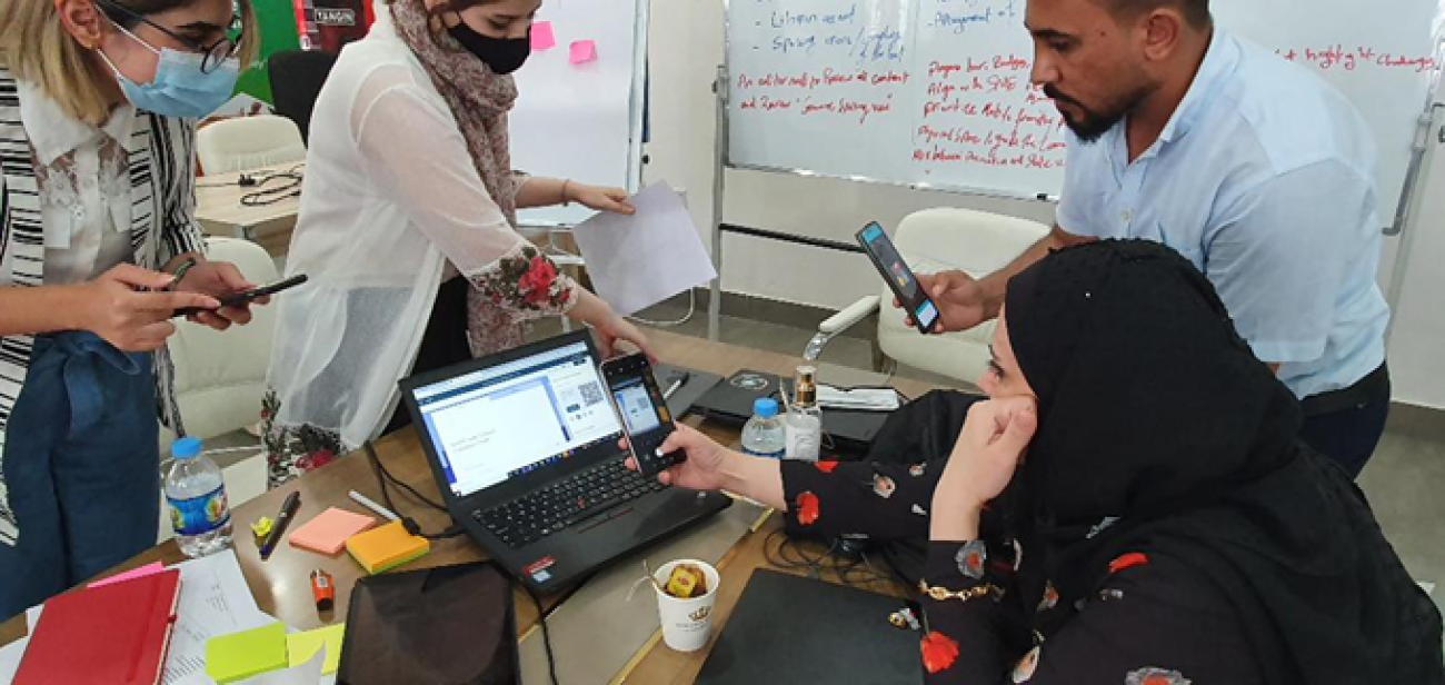 أربعة أشخاص يعملون معًا على جهاز كمبيوتر محمول.