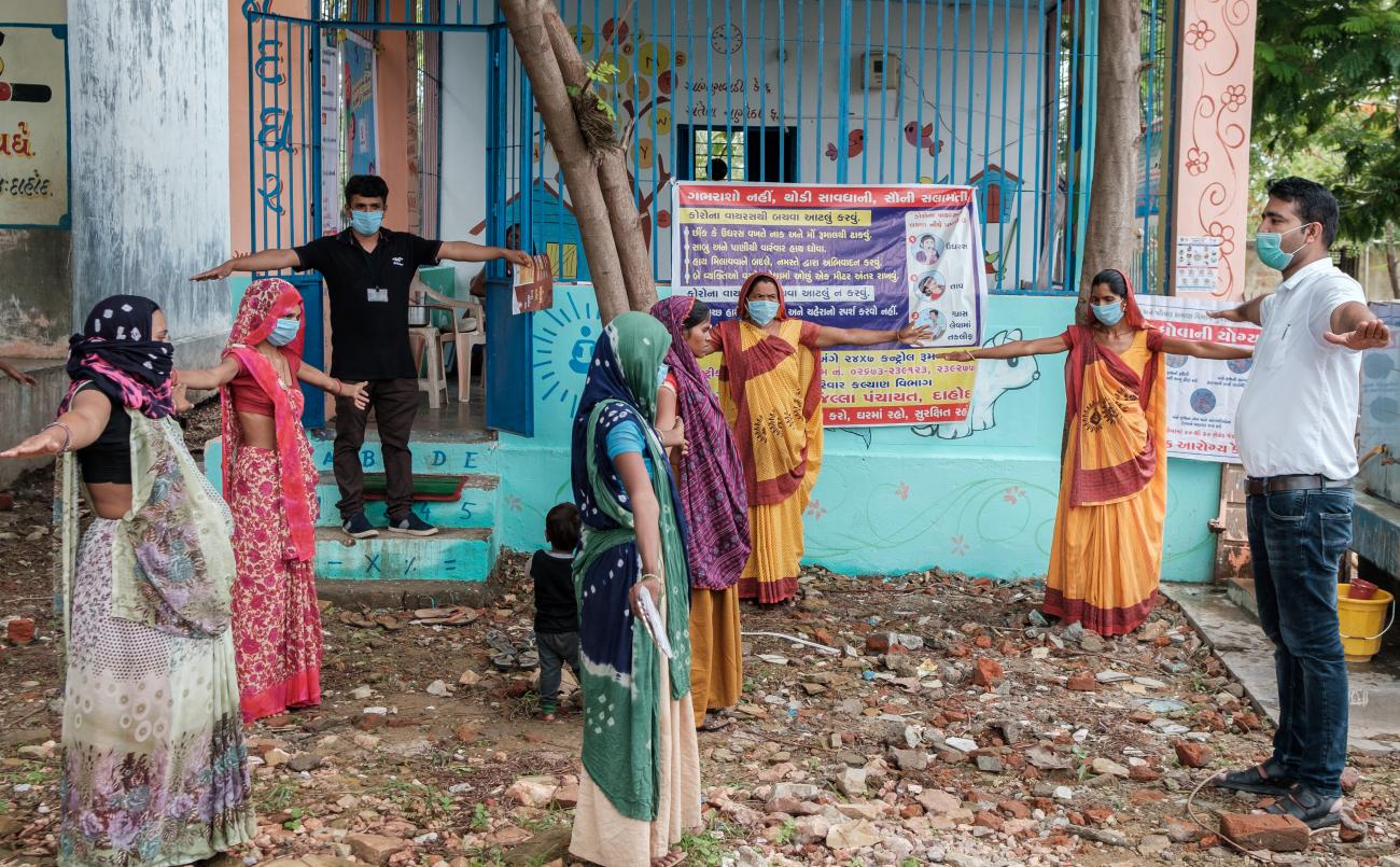 تقف مجموعة من الأشخاص ويفتحون أذرعهم لممارسة التباعد الاجتماعي.