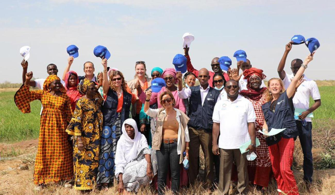Le Coordonnateur résident des Nations Unies au Sénégal, Siaka Coulibaly, pose pour une photo en compagnie des members de l'équipe de pays des Nations Unies lors d'une mission de terrain dans les régions de Saint Louis et Matam, au nord du Sénégal. Les personnes photograhiées arborent un grand sourire et certaines d’entre elles lèvent leur casquette vers le ciel.