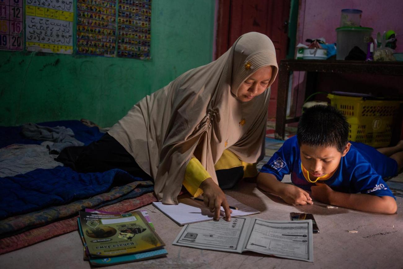 امرأة وطفل ينظران إلى الأوراق الموضوعة على طاولة.