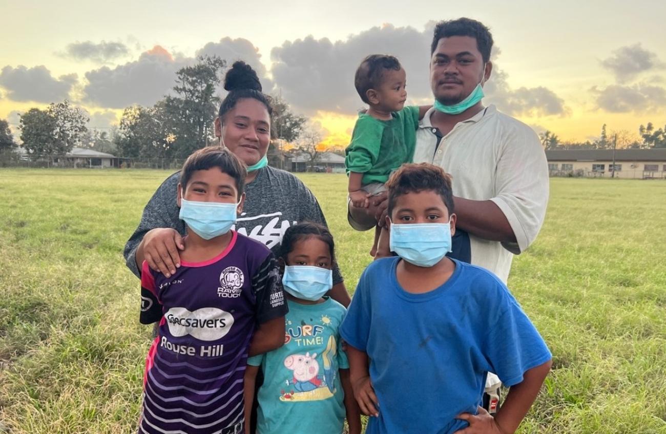Una familia de seis personas se encuentra en el exterior durante la puesta de sol.