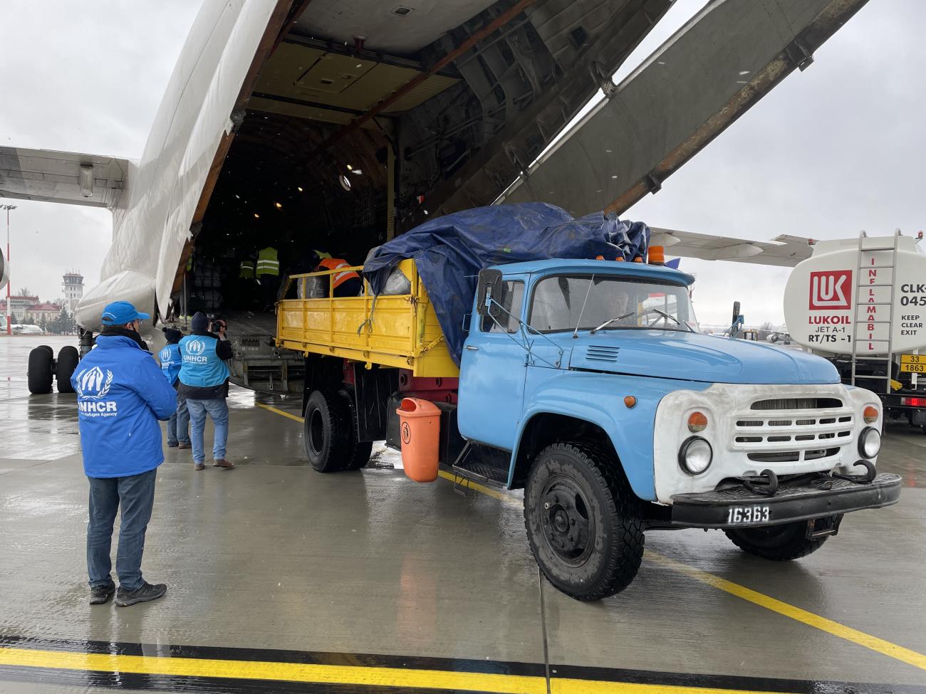 Personas cargando suministros en un avión en la zona del hangar.
