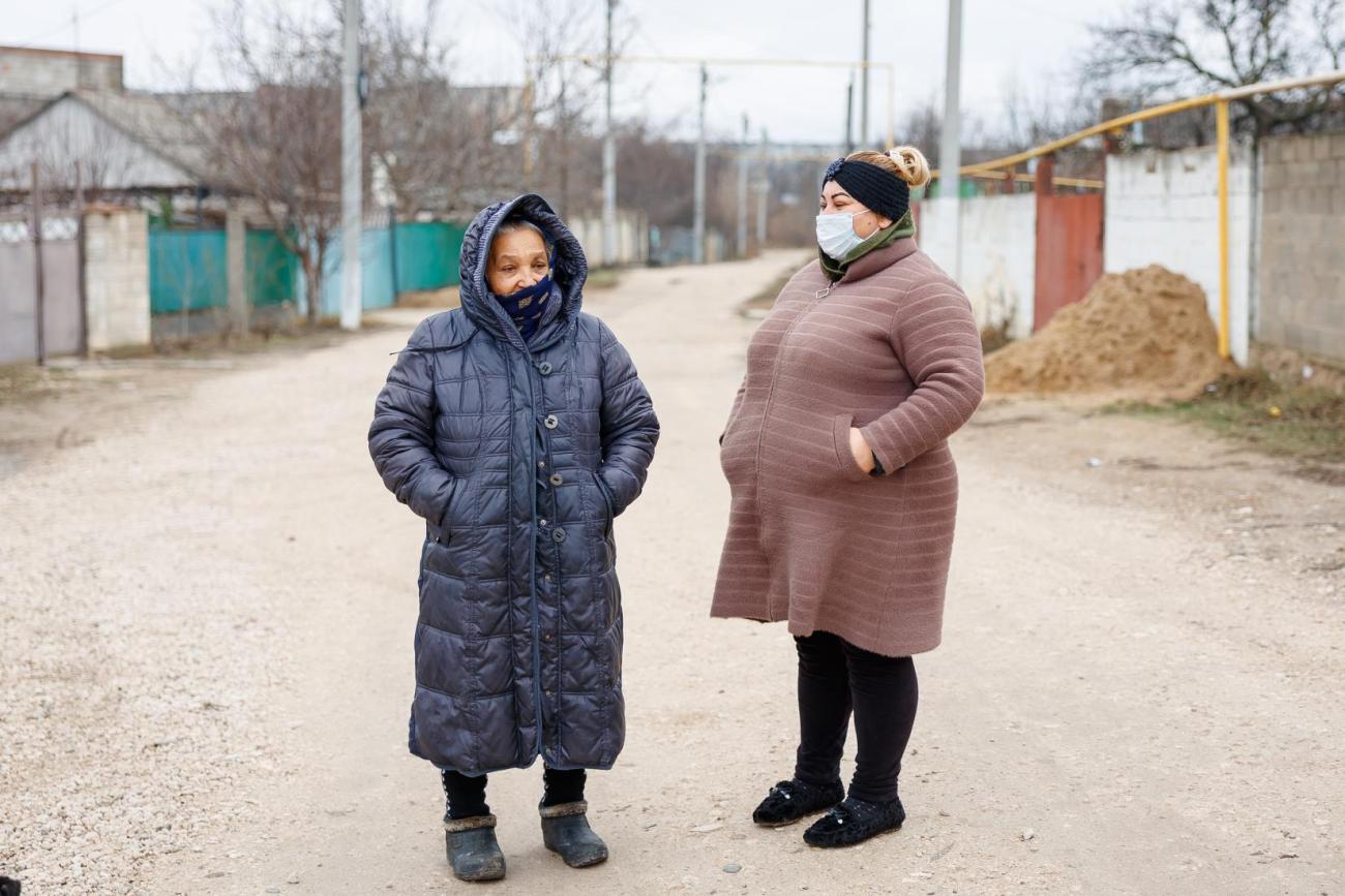 امرأتان ترتديان معاطف شتوية وتتحدثان في الشارع.