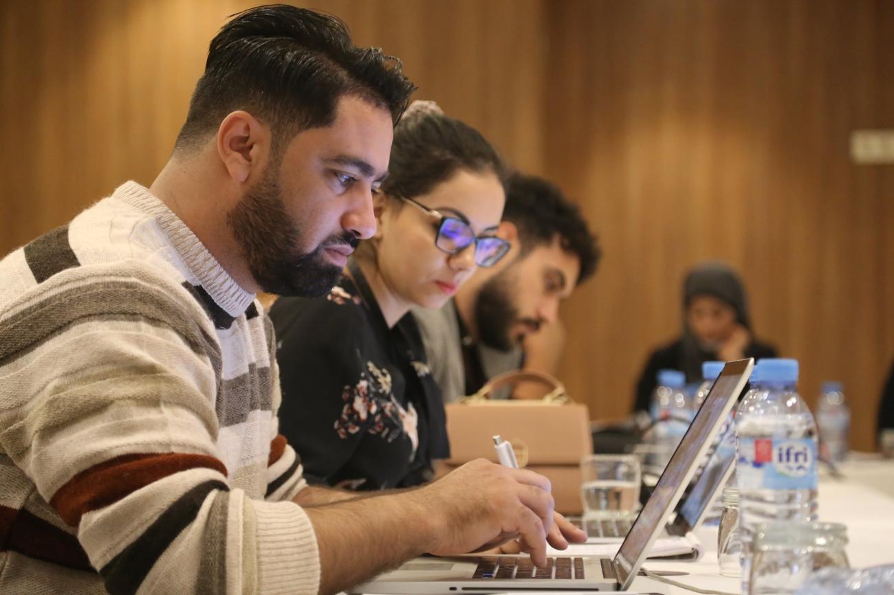 Two young men and a young woman are photographed in profile working side by side in a training room
