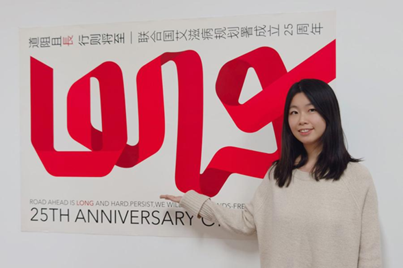 شابة صينية تقف أمام ملصق.