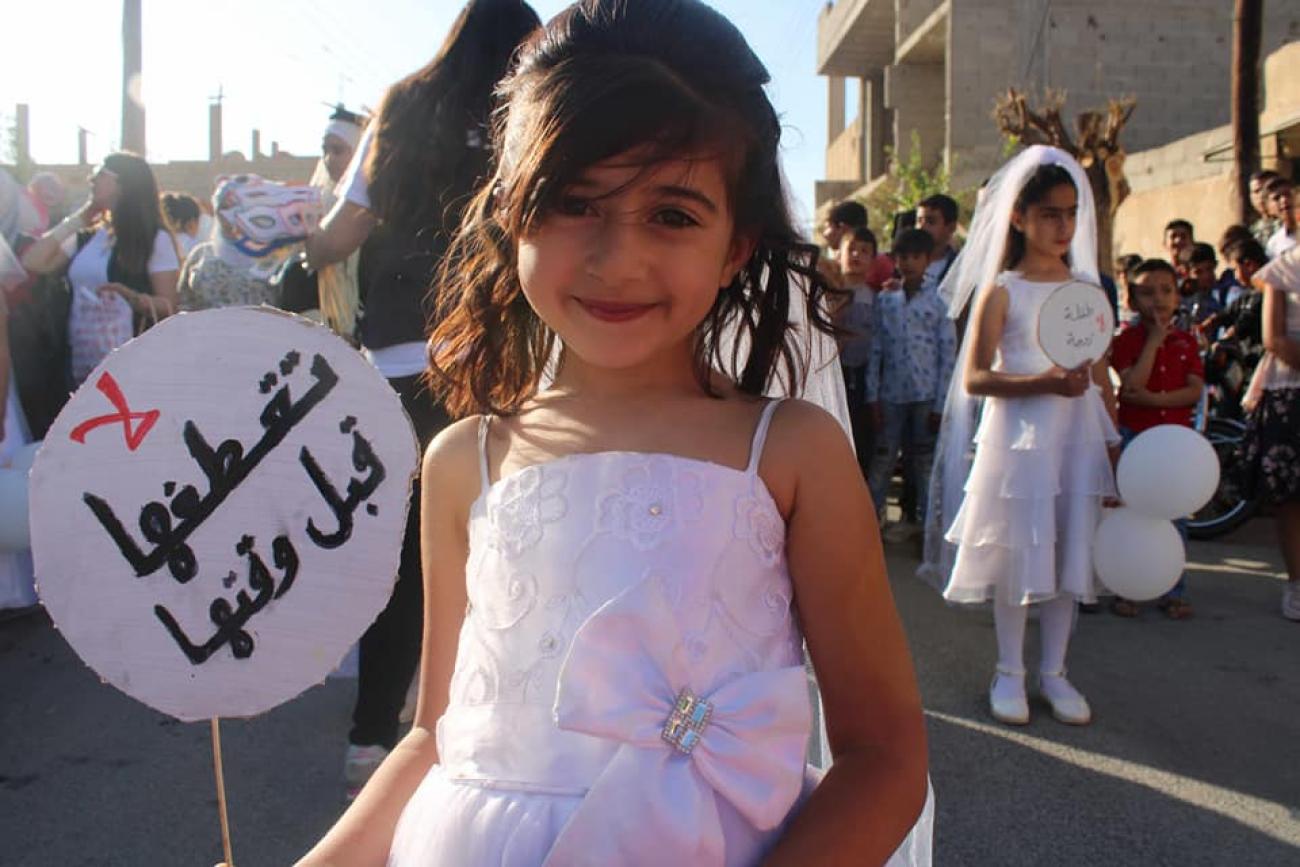 فتاة ترتدي فستان زفاف وتحمل لافتة كتب عليها: لا تقطفها قبل وقتها.