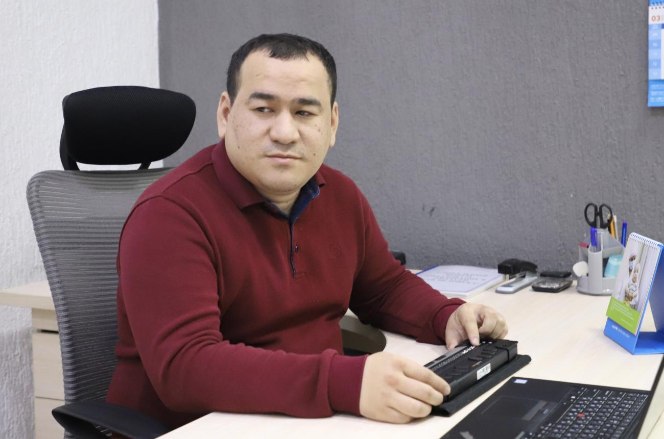 Man sitting at an office desk with a Braille device
