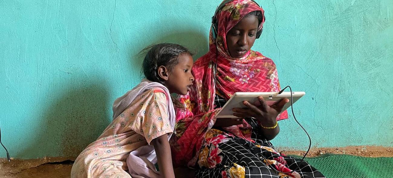 Girls use a solar-powered tablet at an e-learning centre in Jabalain, Sudan.
