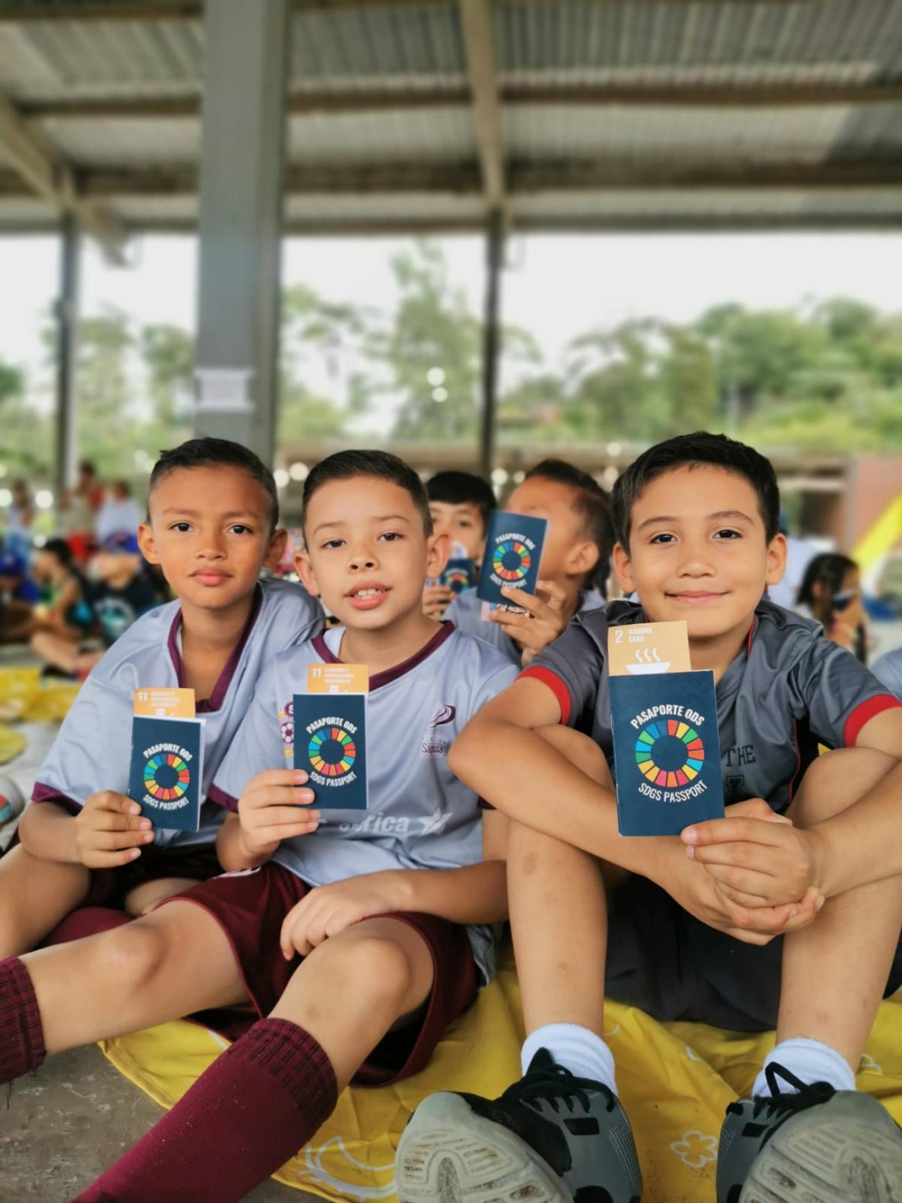 Tres chicos mostrando sus "PASAPORTE ODS"