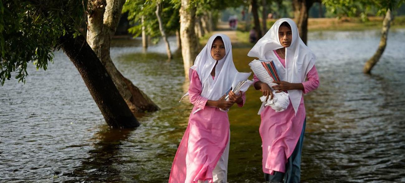 Unas niñas vadean las aguas de la inundación de camino a la escuela en Sunamganj, Bangladesh.