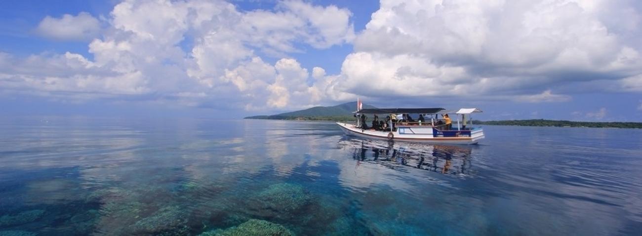 A small boat on a body of water, with bright clouds reflecting on the water