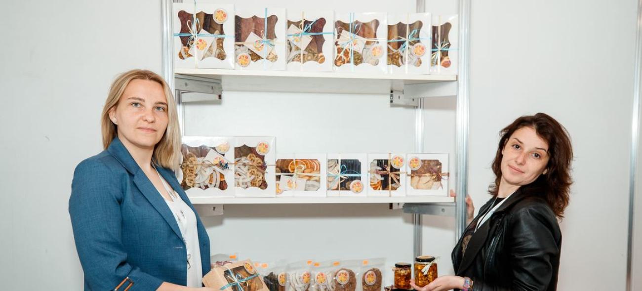 Две женщины на фоне полки с коробками сухофруктов