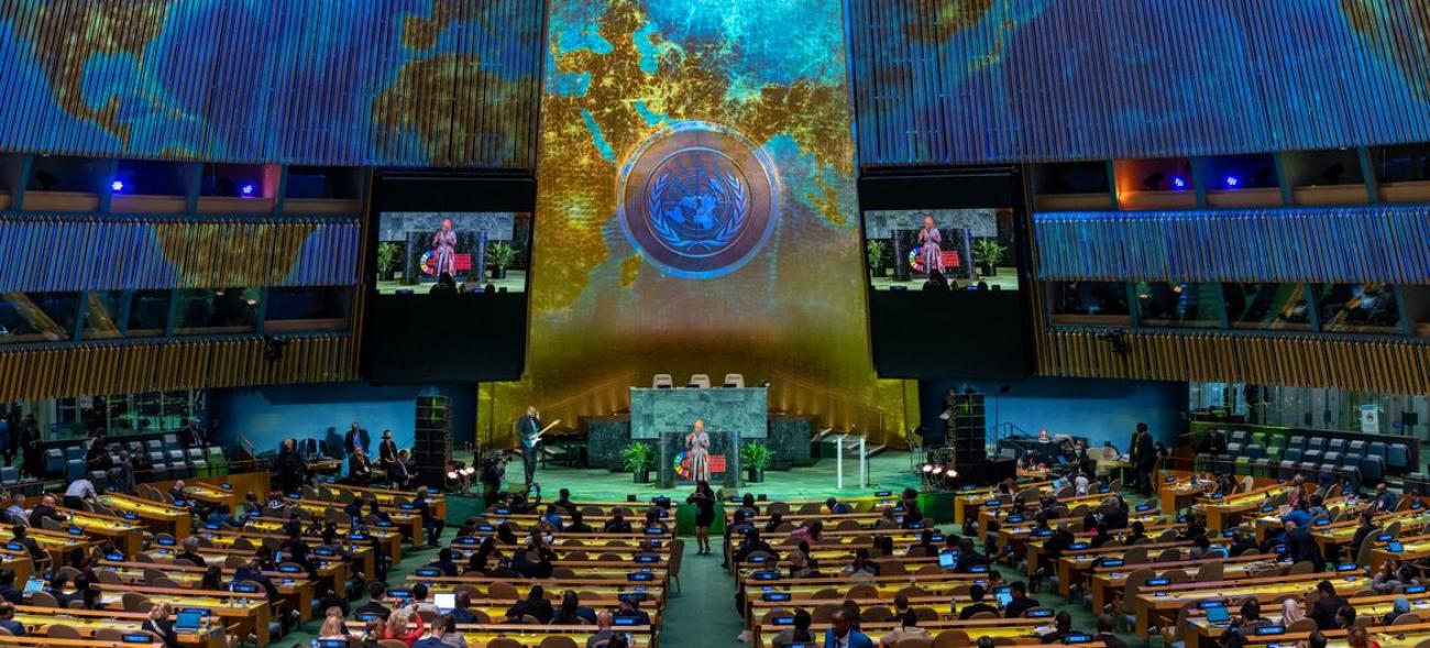 Two people on stage at the UN General Assembly hall. 
