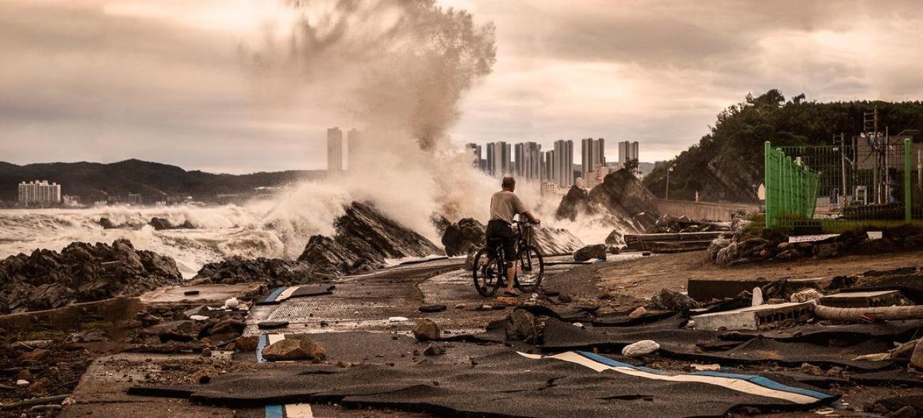 Мужчина на велосипеде едет по дороге, разрушенной землетрясением