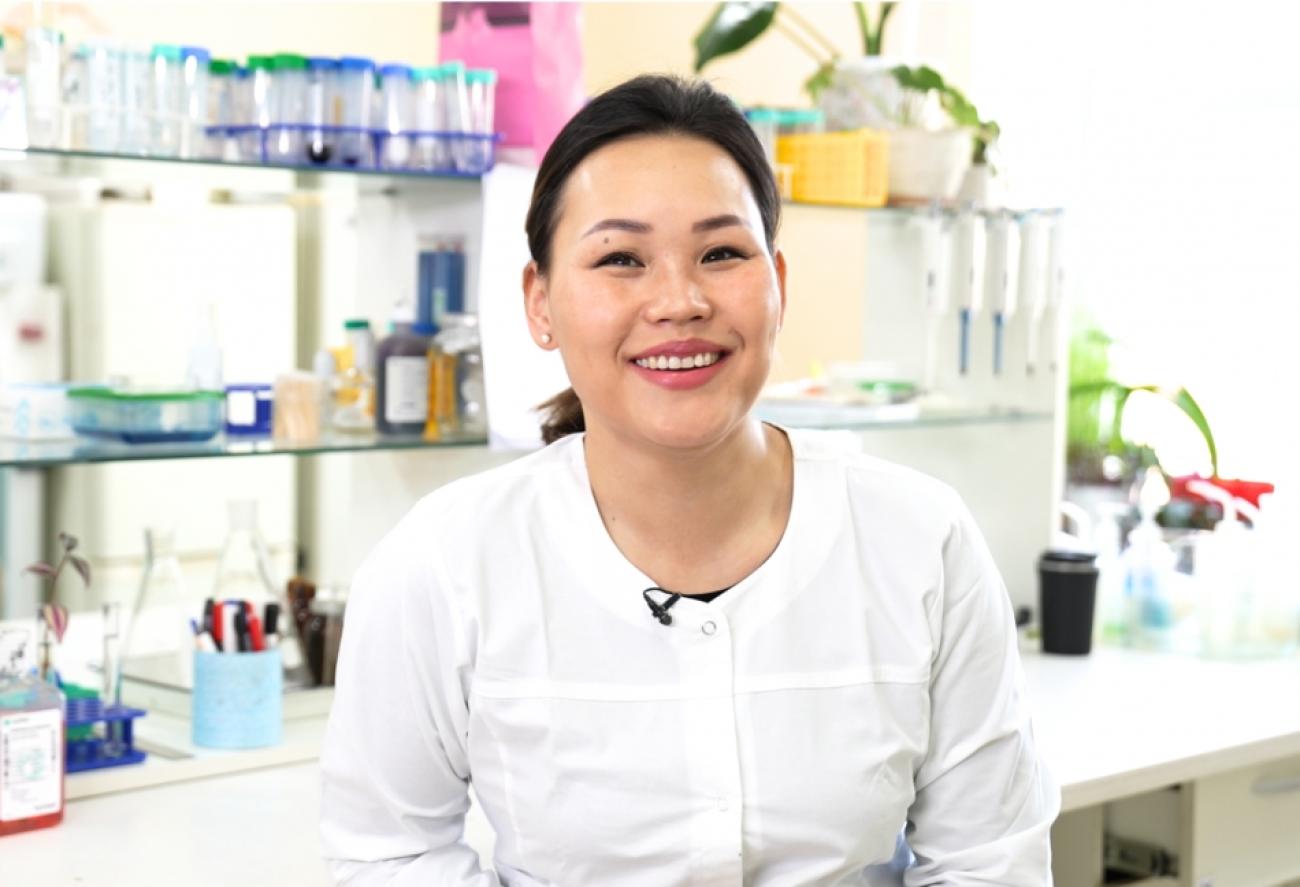 Молодая женщина ученая в лаборатории улыбается на камеру