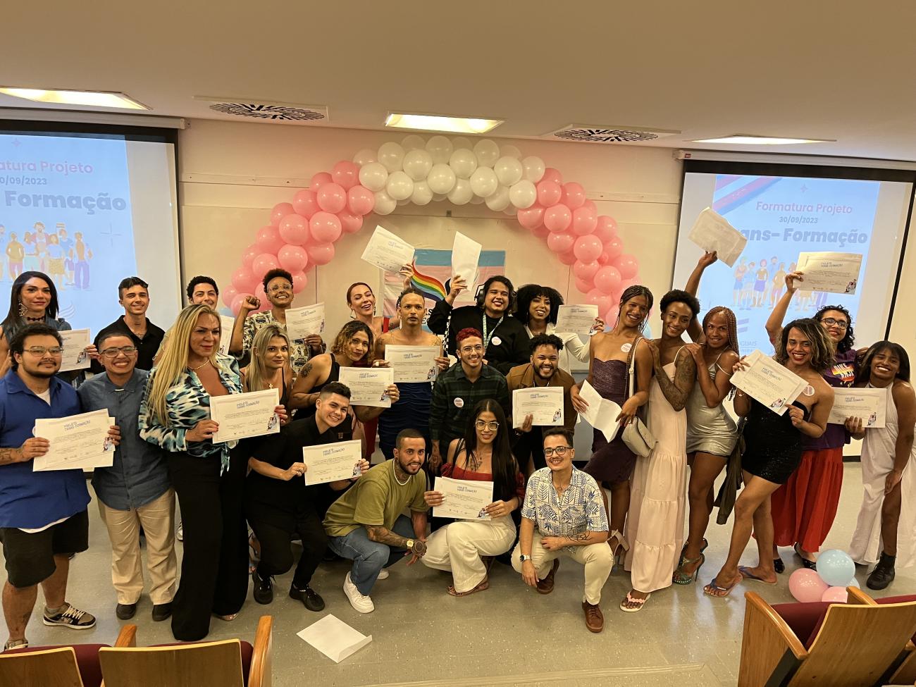 A group of people holding certificates in front of a banner and under a baloon arch