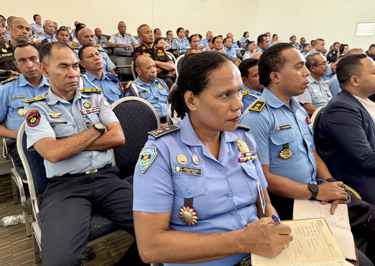 A group of police officers in blue uniforms and badges/ emblems gathered in a meeting room