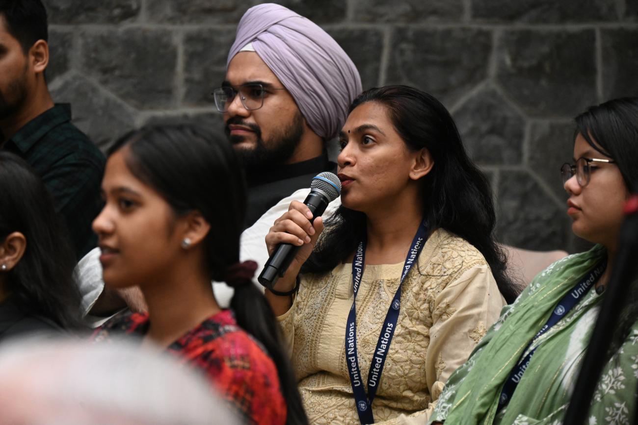 A young woman is holding a microphone and speaking to an audience